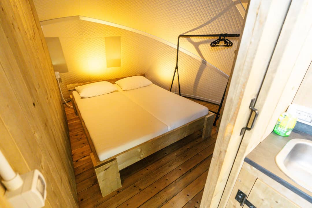 Slaapkamer met tweepersoonsbed en houten wanden