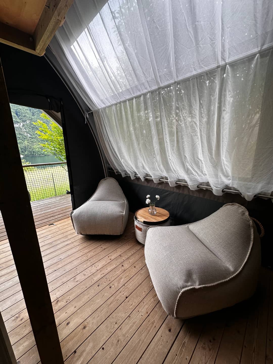 Zithoek met poefs onder het lichte gordijn in de Big Oak Lodge XS