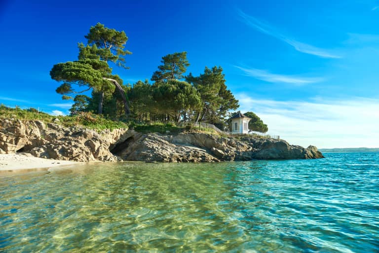 Rotsen met dennen in turquoise water aan de kust van Bretagne