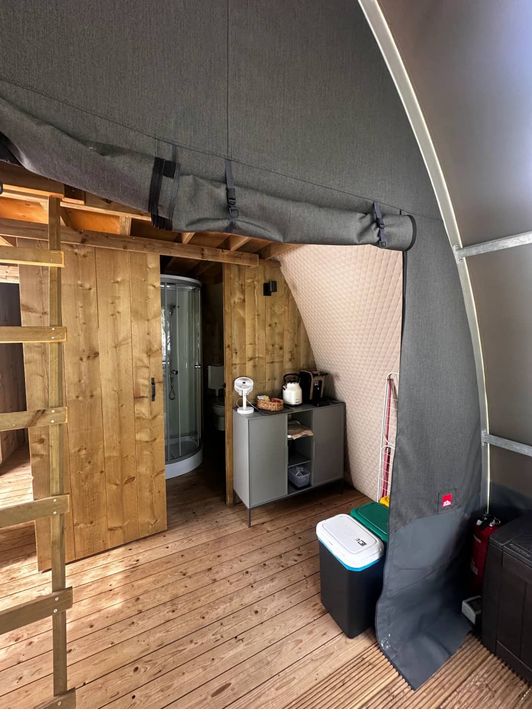 Binnen in de Big Oak Lodge XL: houten deur naar de douchecabine en een kastje met waterkoker en broodrooster