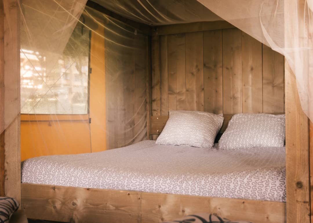 Tweepersoonsbed in de Base Lodge met houten wand