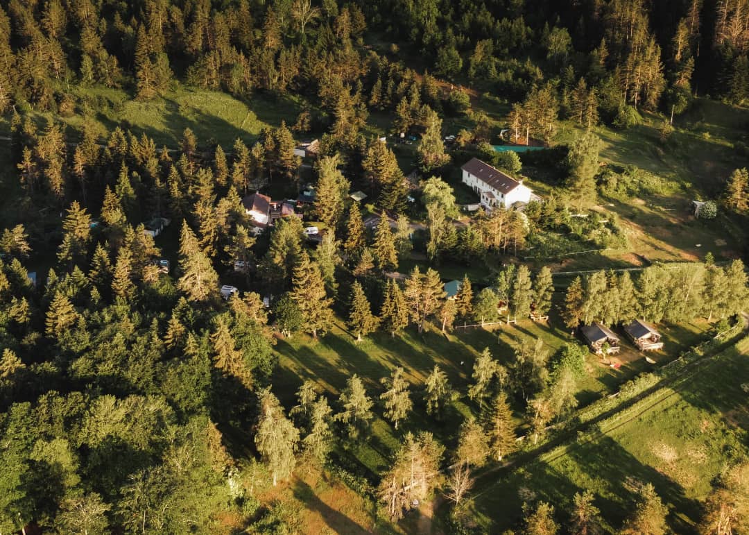 Luchtfoto van de camping met de lodges tussen de bomen