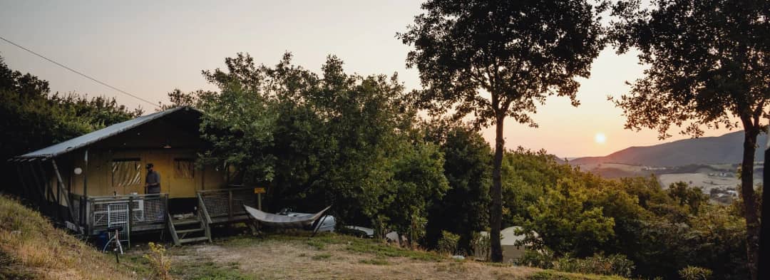 Zwembad van Camping Casa Tartufo met zwemmers, rode ligbedden en uitzicht over de groene heuvels van Le Marche