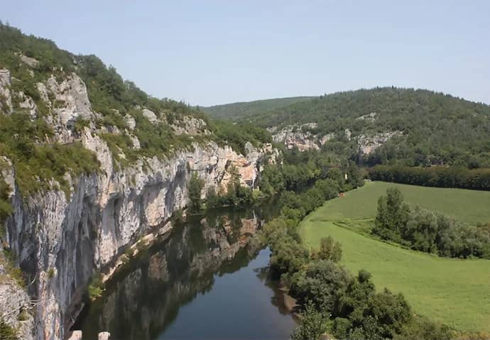 Rivier tussen steile kalkrotsen en groene weiden, van bovenaf gezien in een dal in de Dordogne
