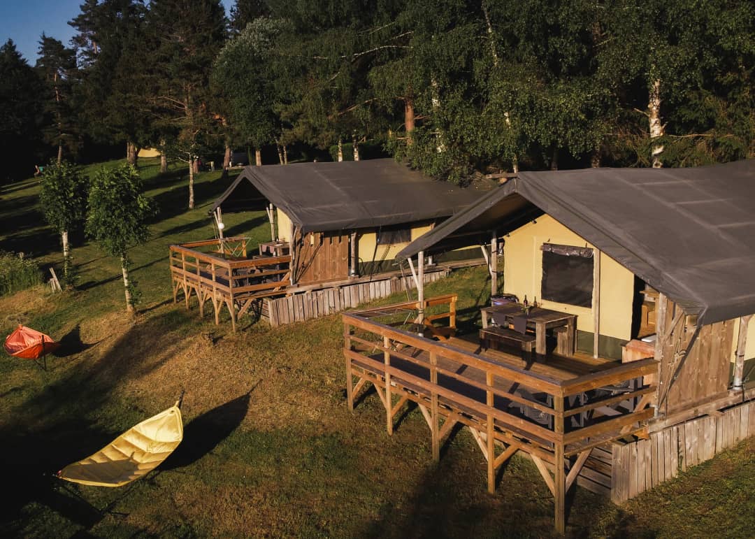 Twee Base Lodges op palen met terras in de avondzon op Les Sapins