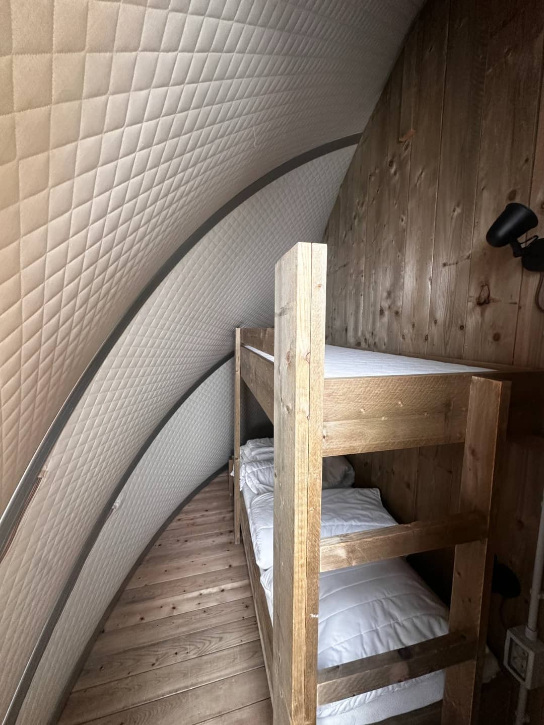 Houten stapelbed met wit beddengoed onder de gewatteerde, gebogen wand van de Big Oak Lodge XL